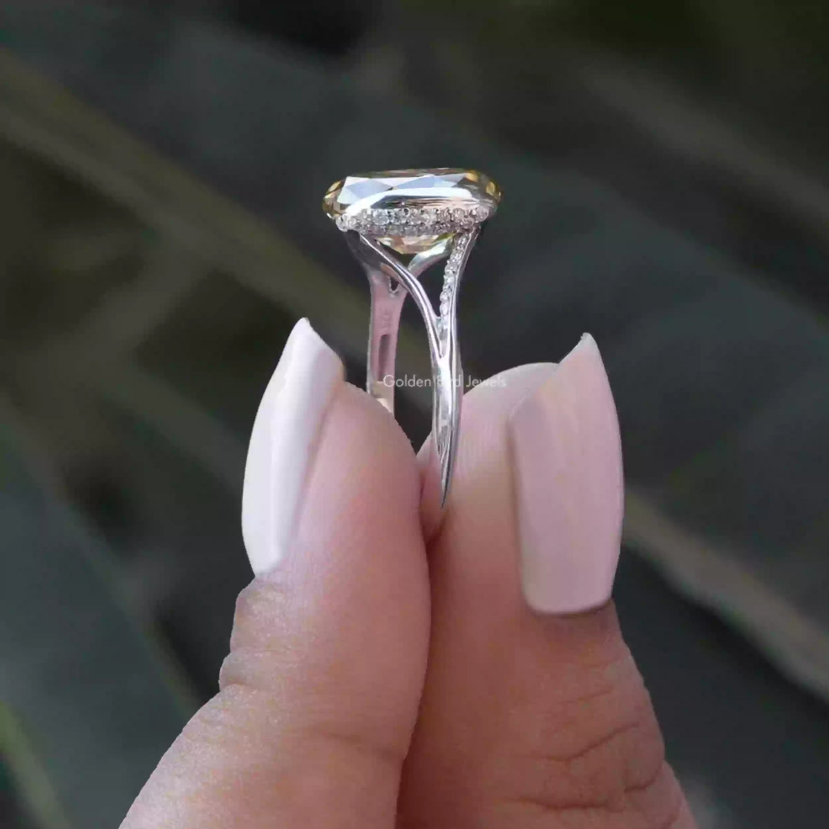 Side View of Oval Cut Bezel Set Engagement Ring In two fingers