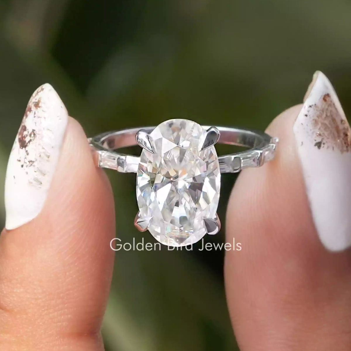 Front view of Crushed Ice Oval And Baguette Cut Moissanite Accent Set Ring in two fingers