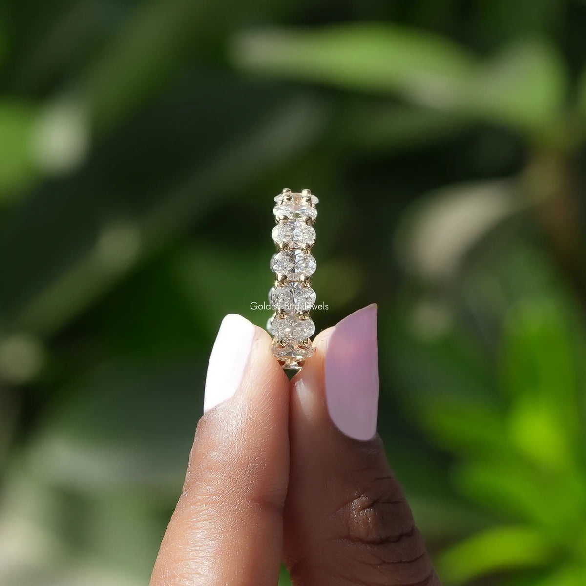 Side View of Oval Cut Diamond Eternity Wedding Band In two fingers