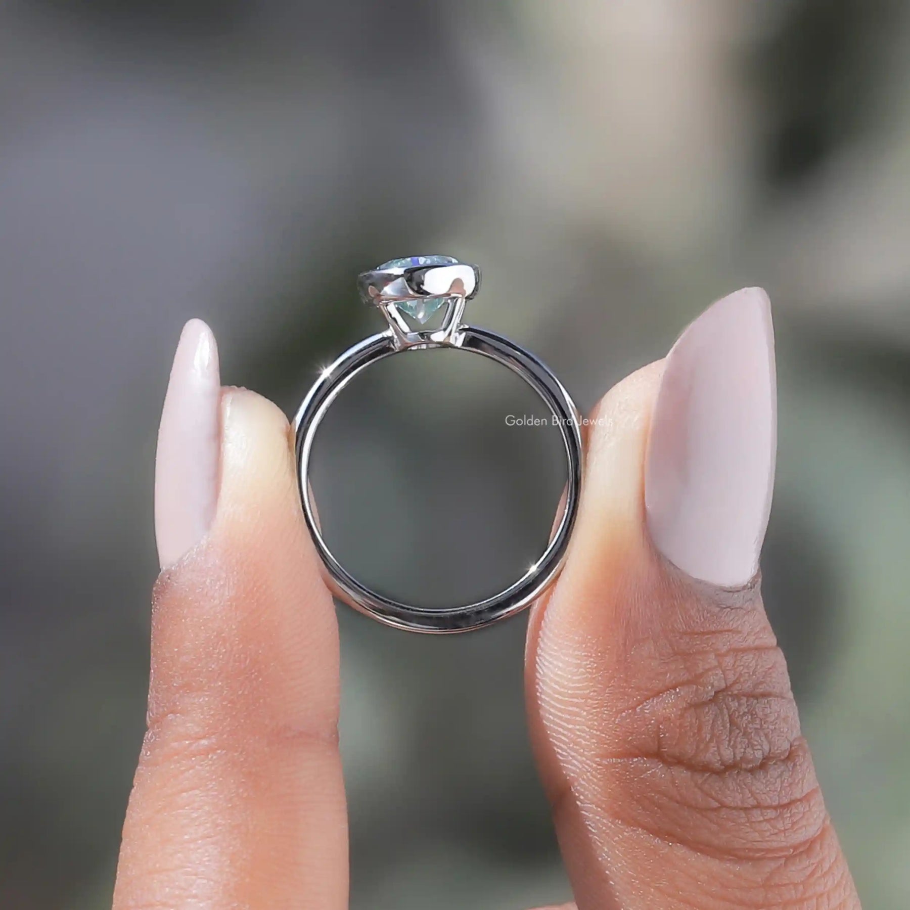 Back View of Oval Cut Moissanite Bezel Setting Solitaire Ring In two fingers