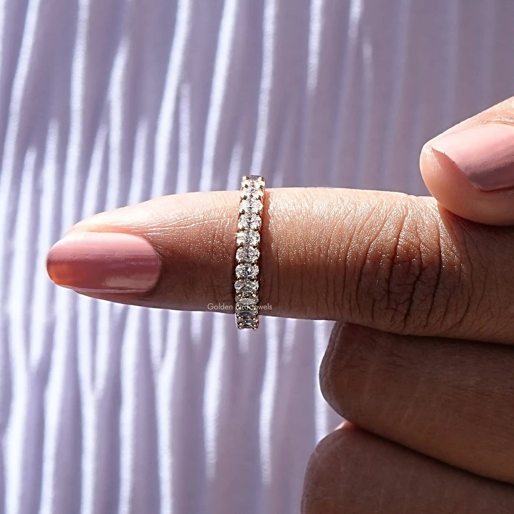 In finger front View of Oval Cut Lab Diamond Eternity Band In Yellow Gold