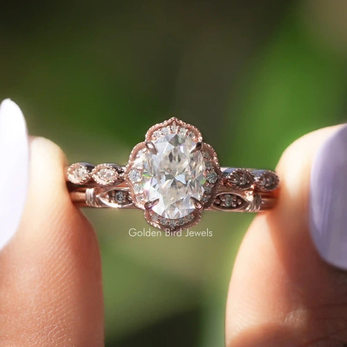 Two fingers holding the Moissanite Oval Halo Wedding Ring