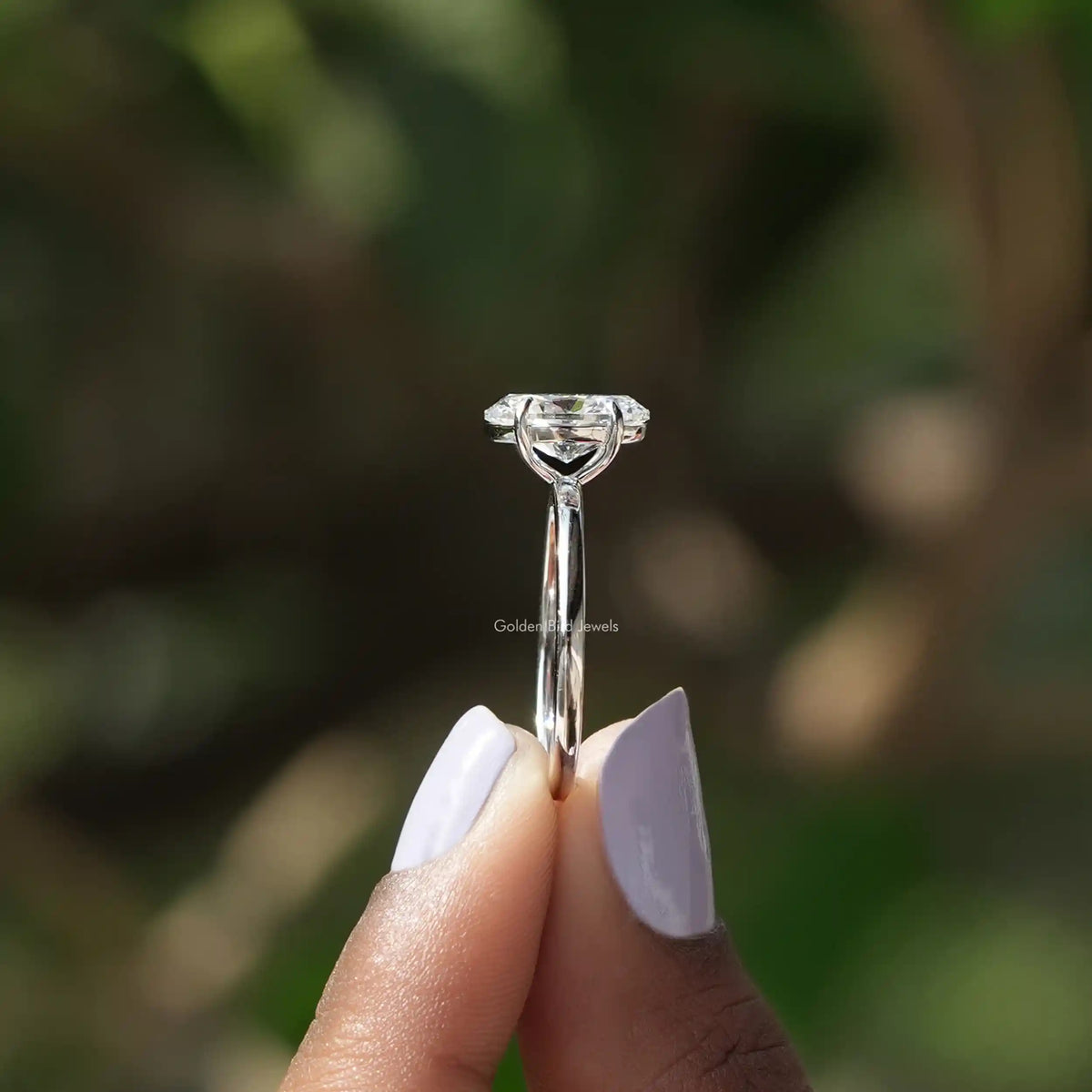 Side View of Oval Cut Diamond Solitaire Ring In two fingers