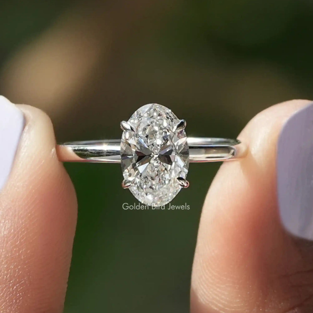 Two fingers holding the Oval Cut Lab Diamond Solitaire Engagement Ring