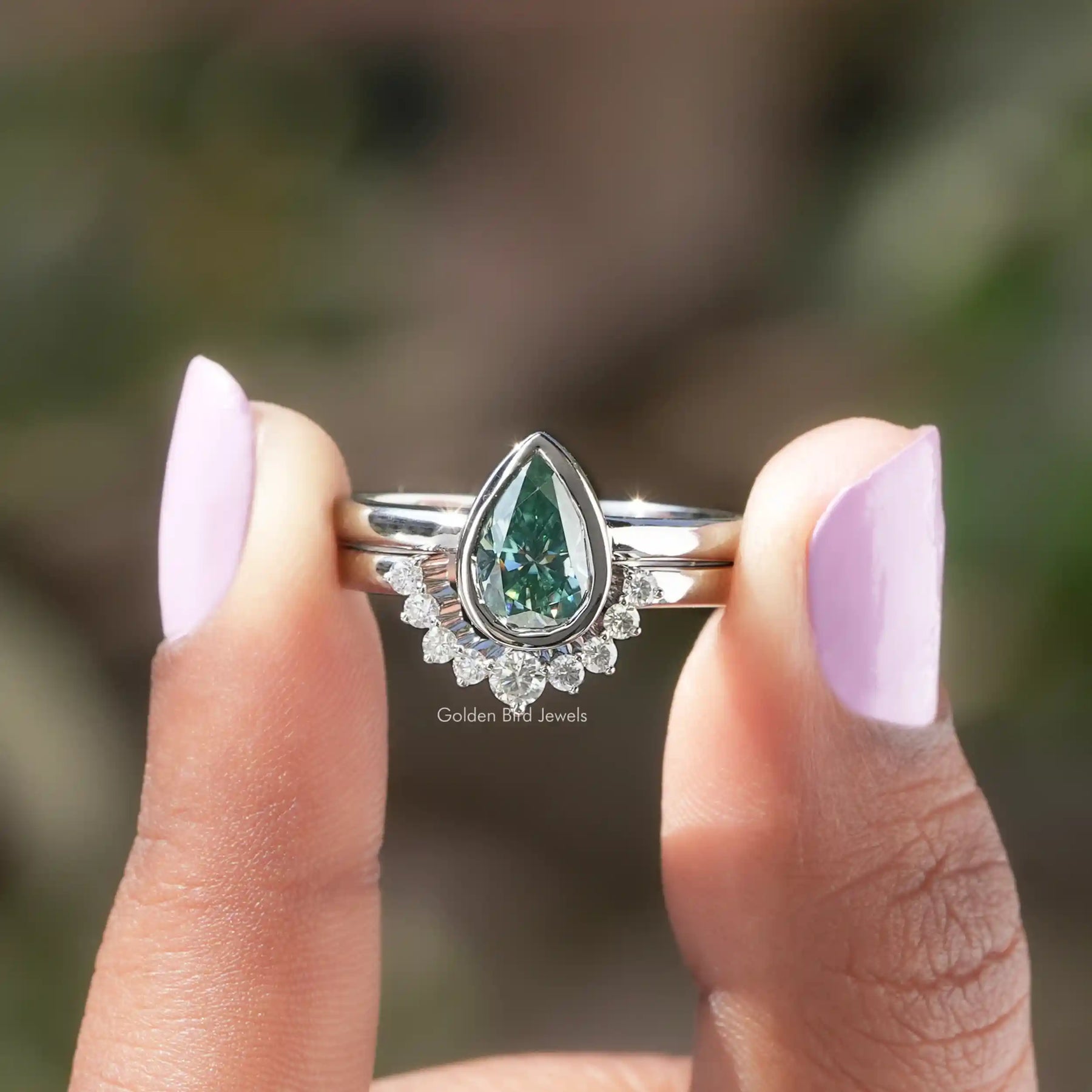 Two fingers holding the Pear Cut Moissanite Bridal Ring