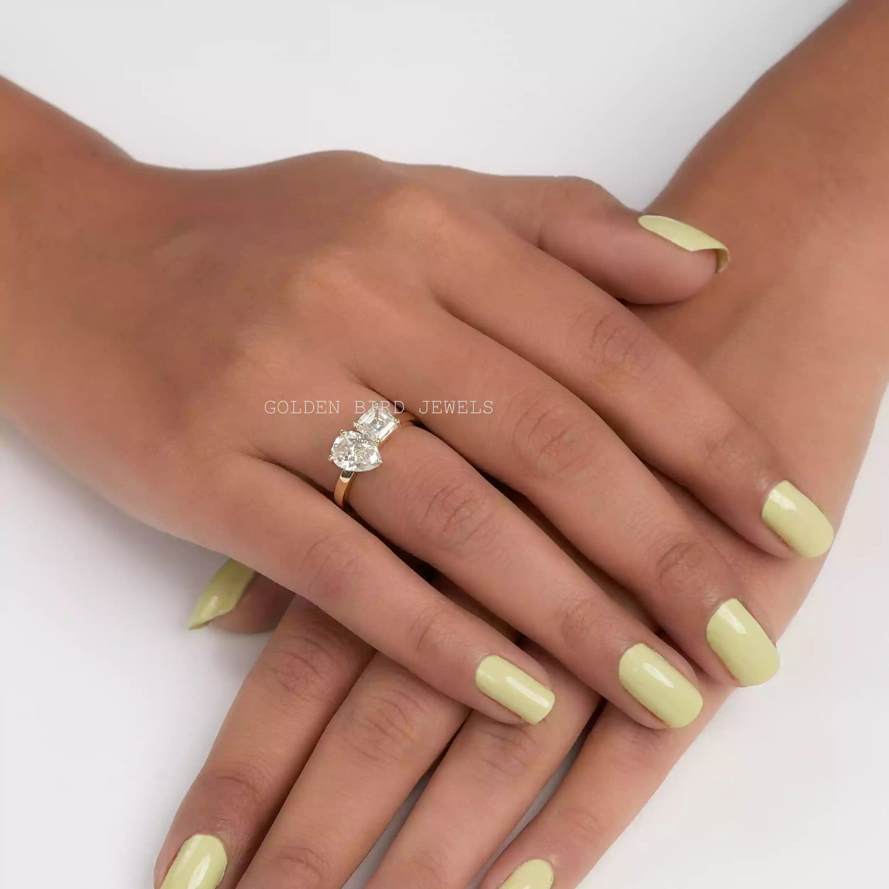 In finger front view of Asscher and pear cut moissanite ring in prongs setting