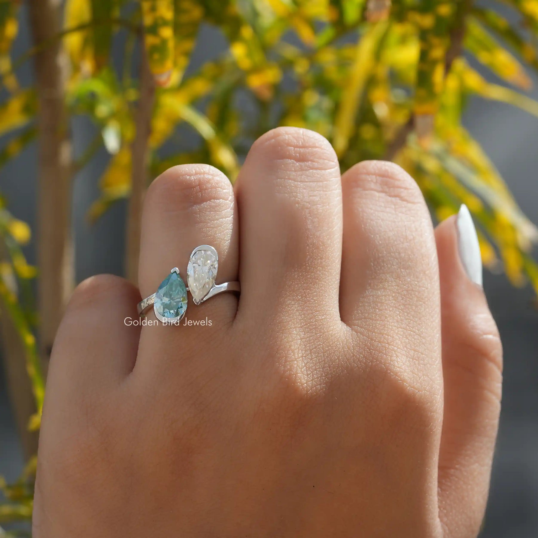 Finger view of a pear cut moissanite engagement ring