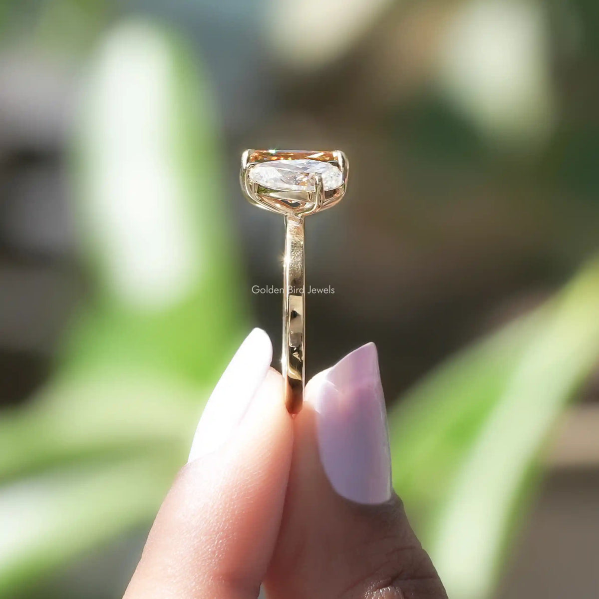 side view of Toi et Moi fancy colored ring on holding two fingers