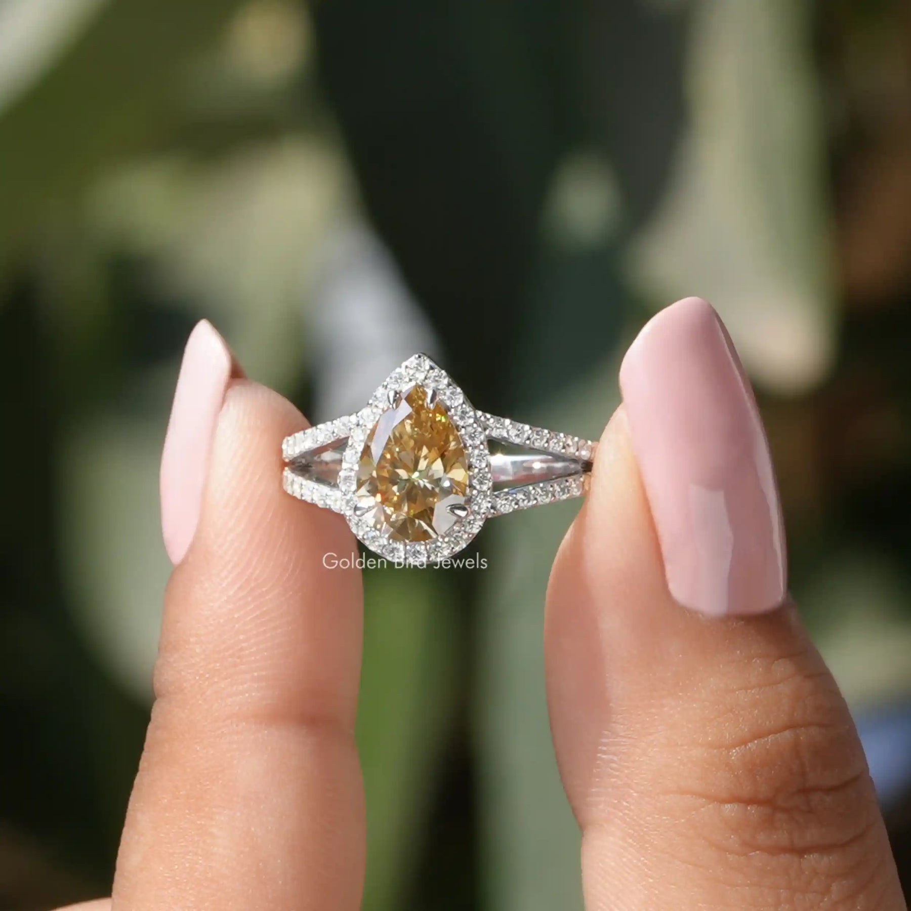 Two fingers holding the Pear Cut Moissanite Engagement Ring