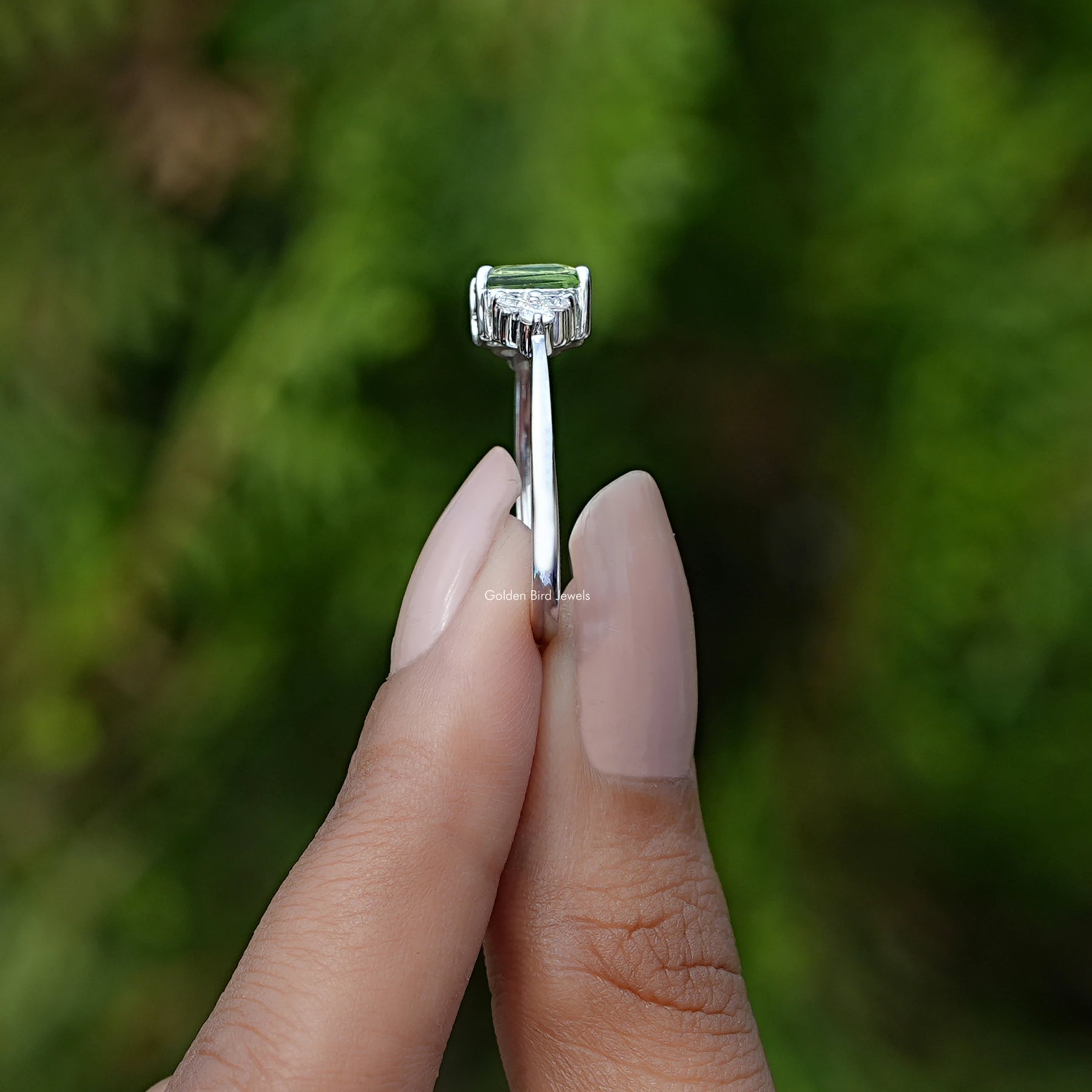 Side View of Peridot Green Emerald Gemstone Ring In two fingers