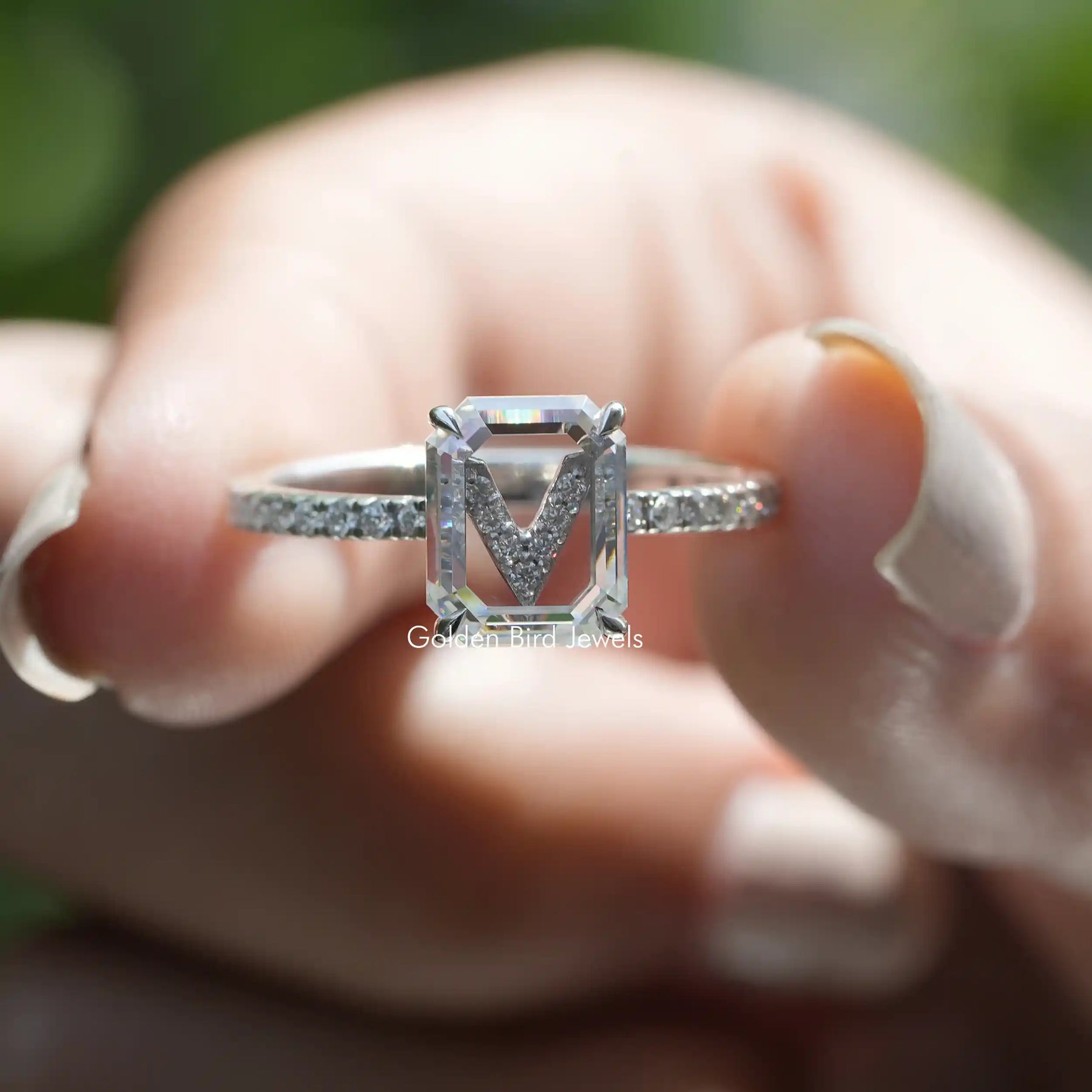 Two fingers holding the Emerald Cut Moissanite Engagement Ring