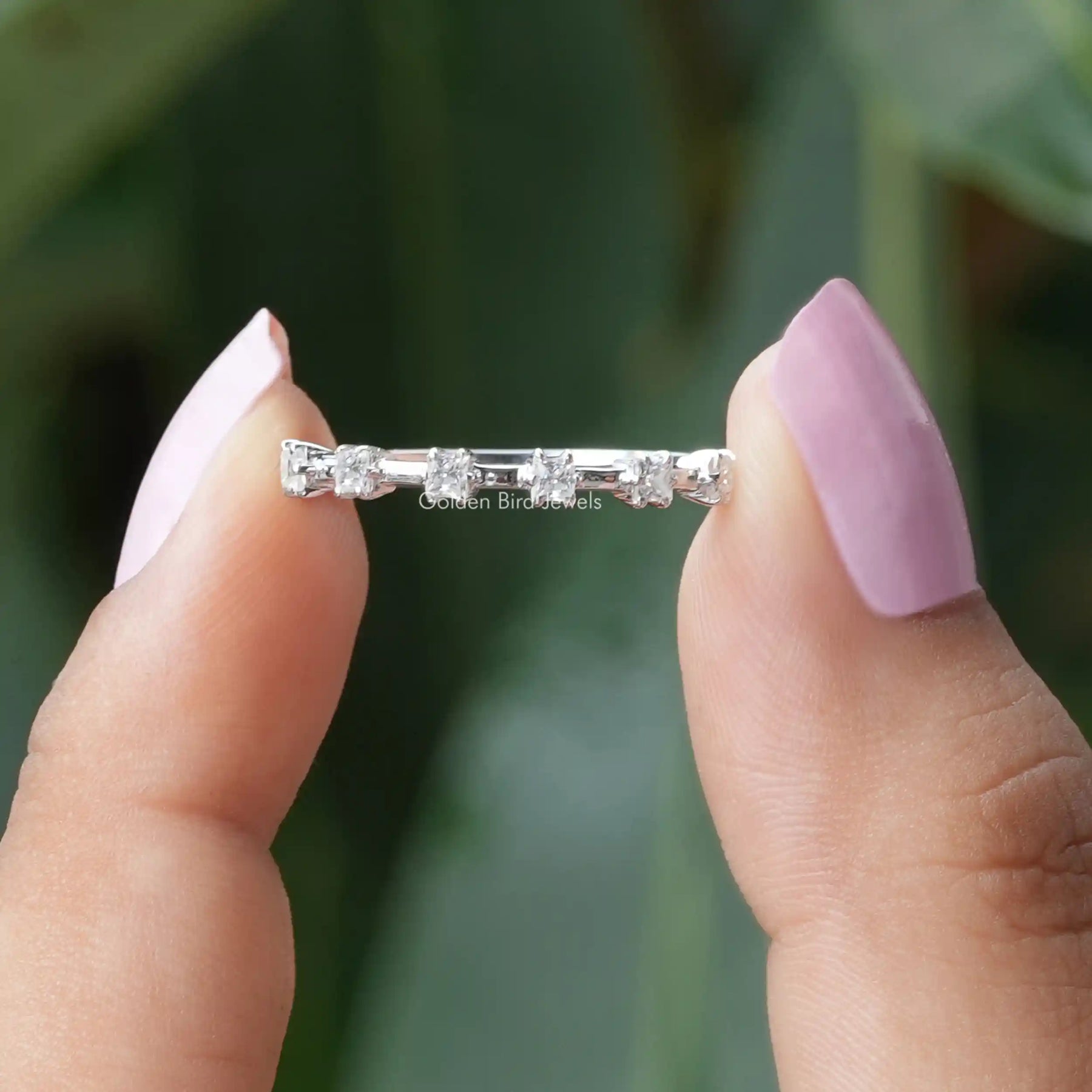 Two fingers holding the Princess Cut Half Eternity Wedding Band
