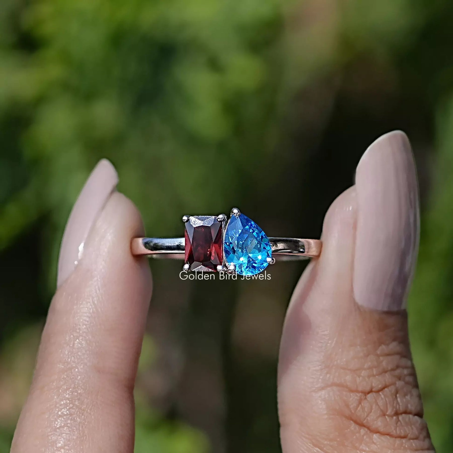 Front view of Radiant And Pear Gemstone Two Stone Ring in two fingers