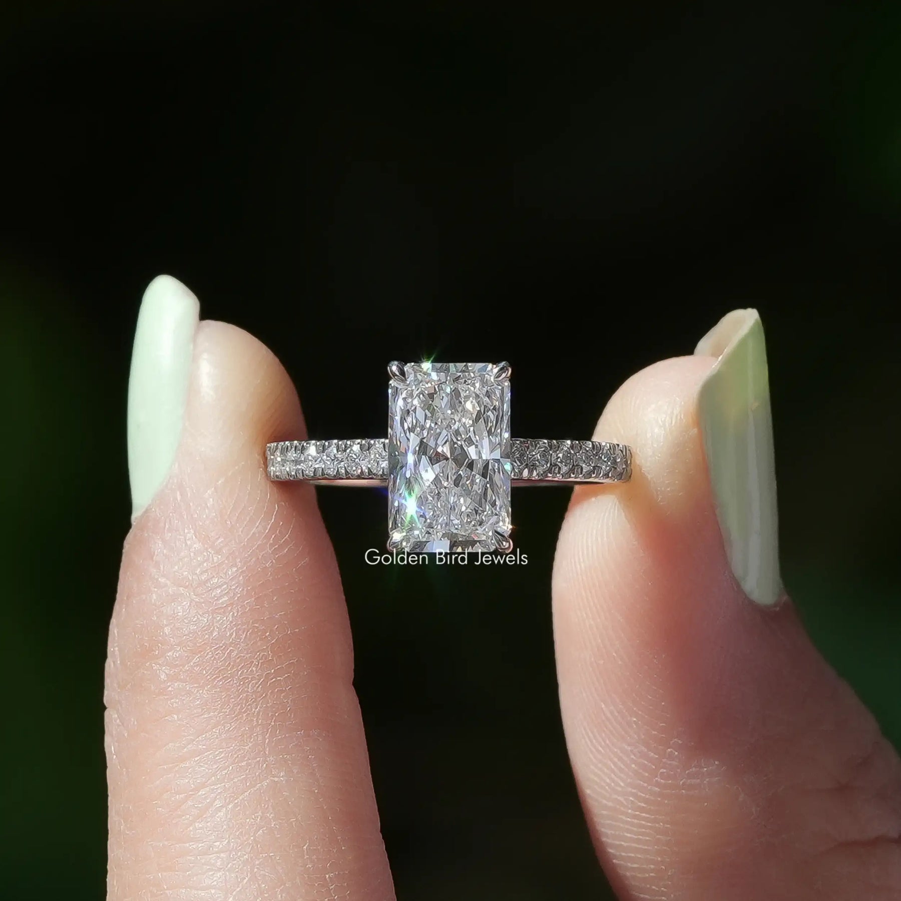 Two fingers holding the Radiant Cut Solitaire Accent Diamond Ring
