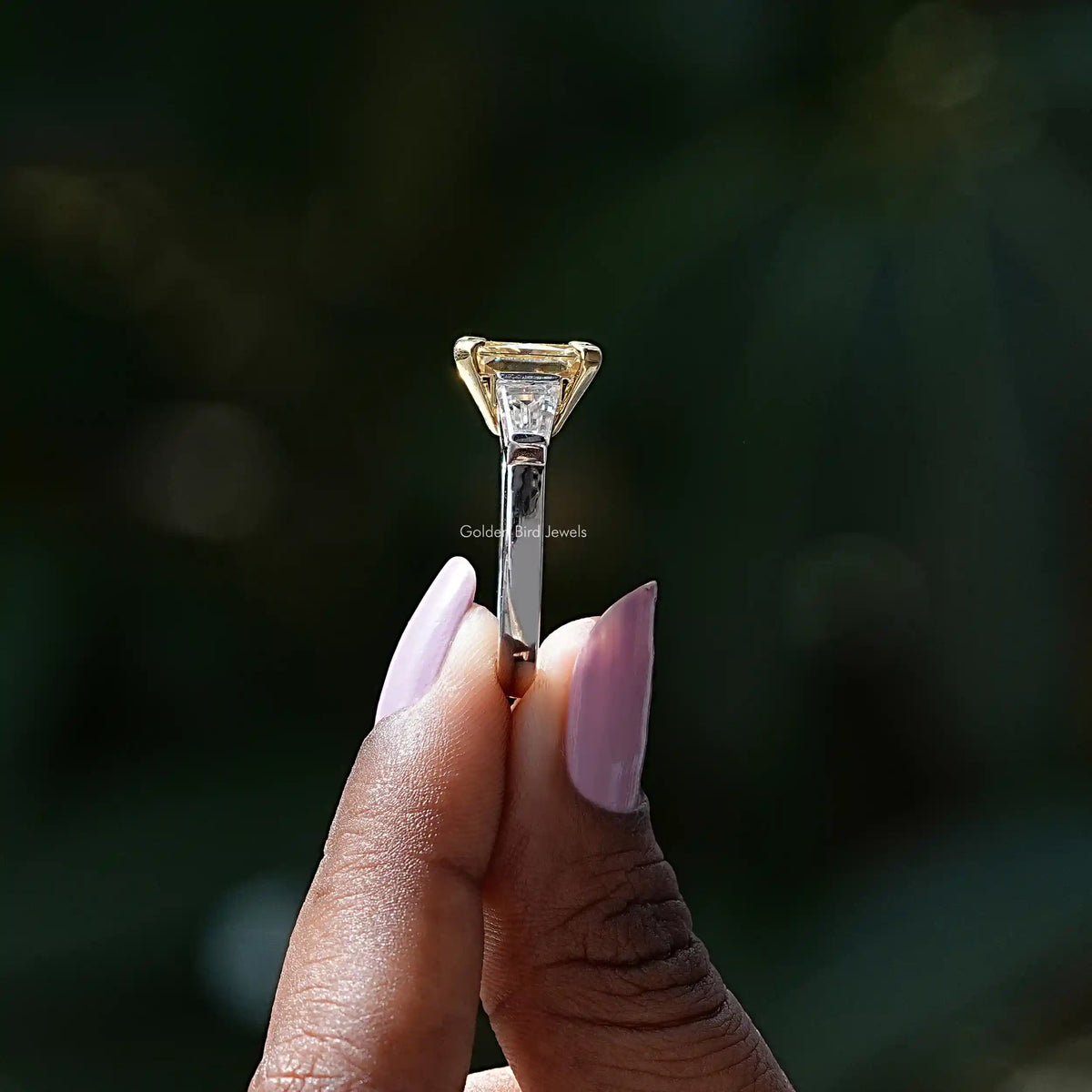 Side View of Radiant And Tapper Baguette 3 Stone Ring In two fingers
