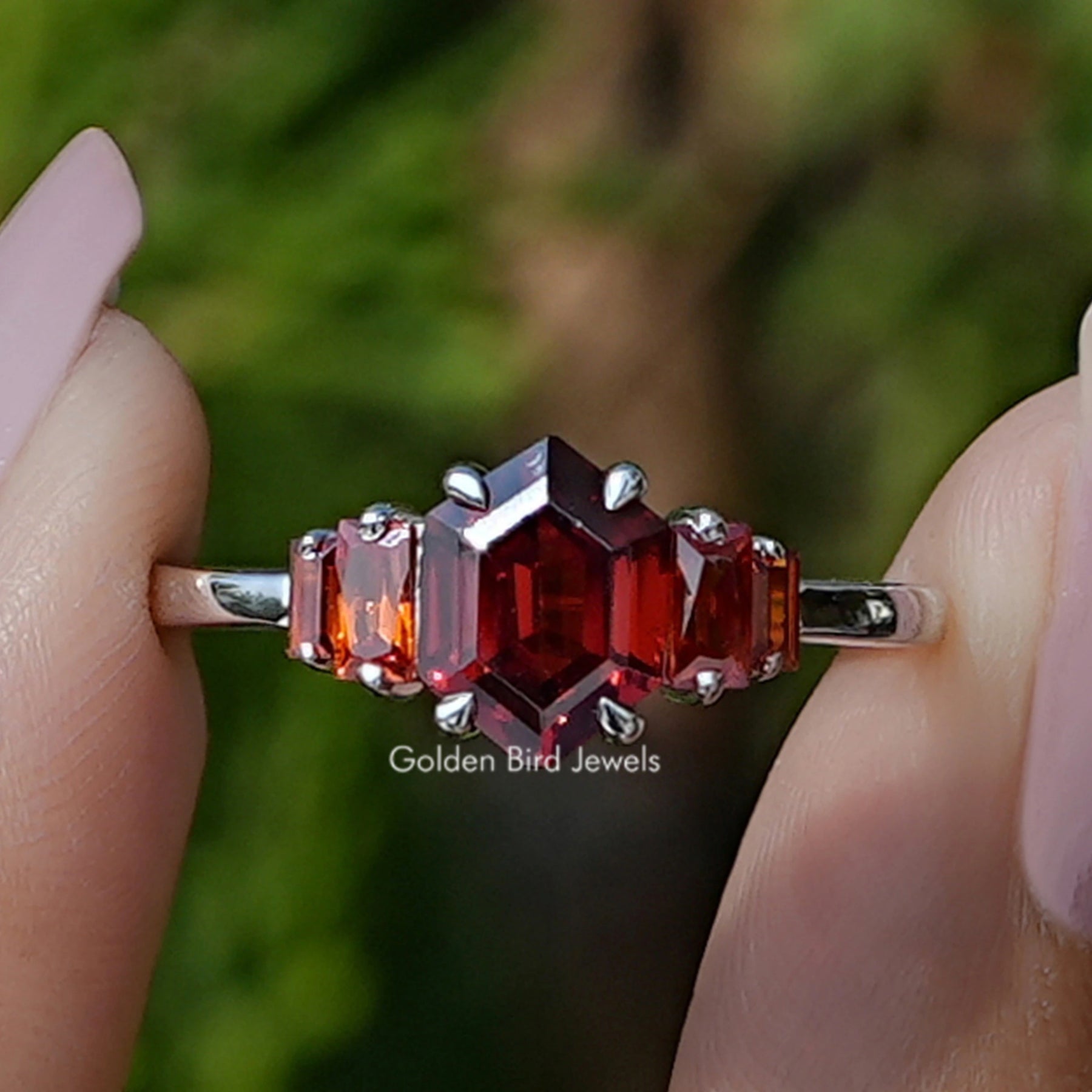Front view of Red Ruby Hexagon Cut Gemstone 5 Stone Ring in two fingers