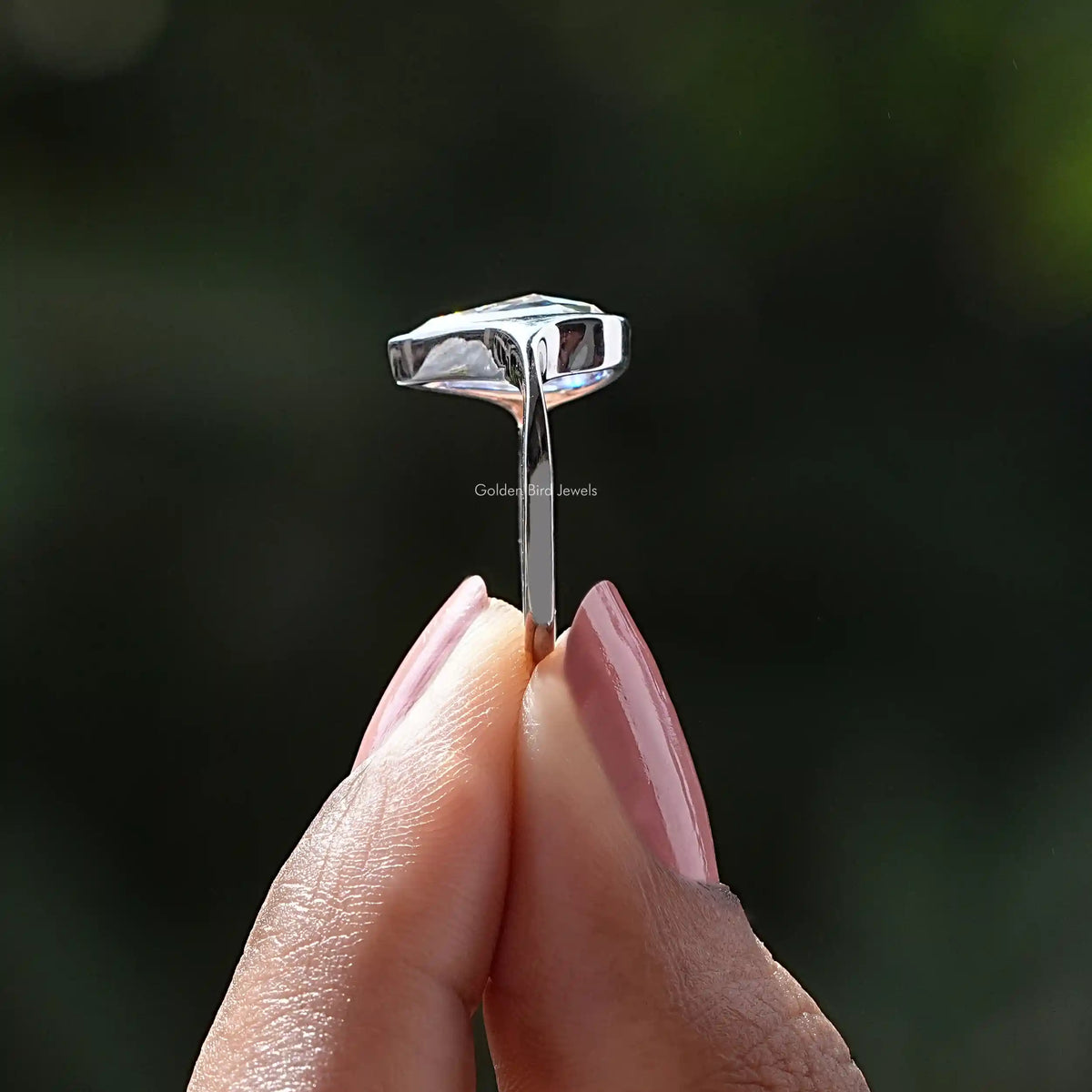 Side View of Pear Cut Moissanite Bezel Set Ring In two fingers