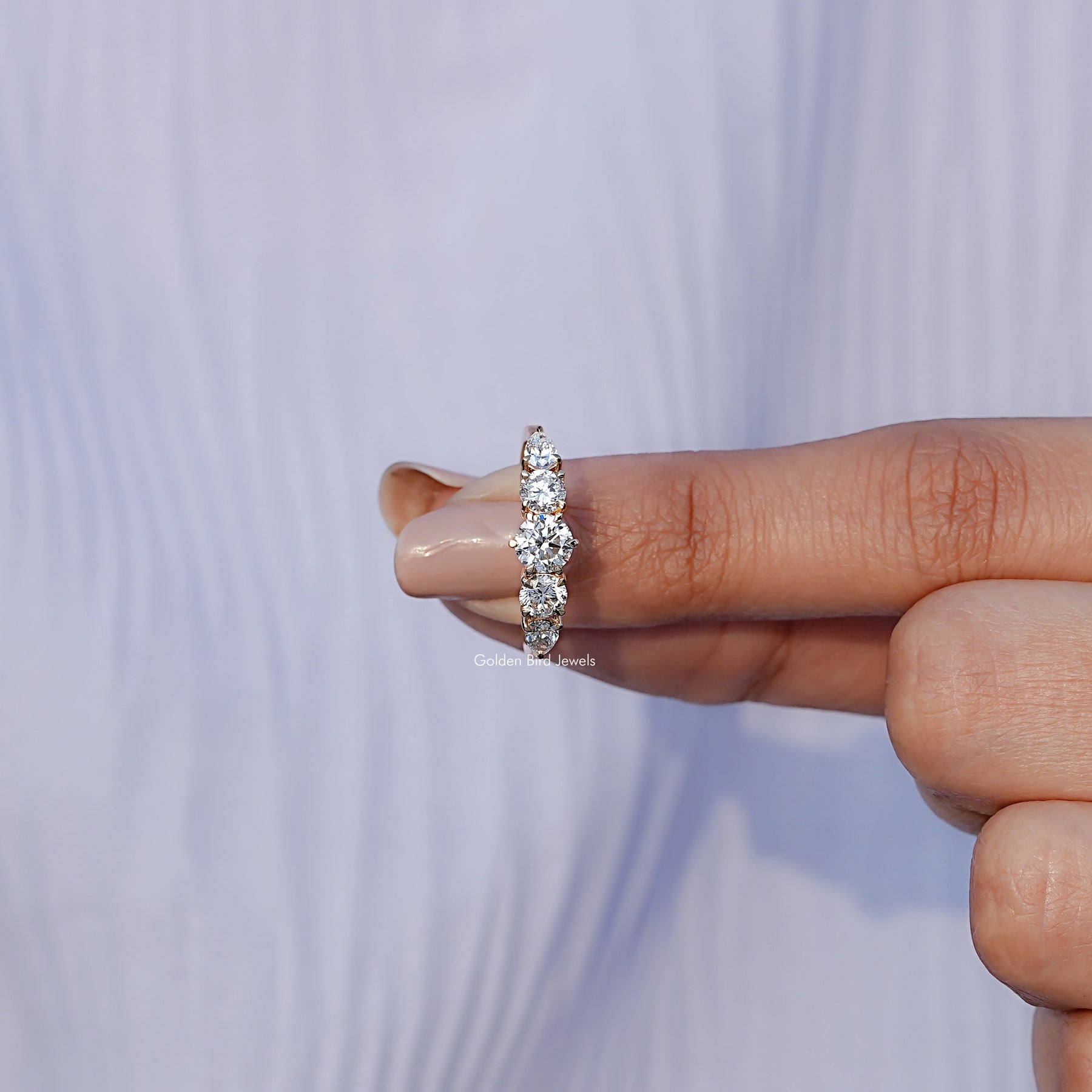 In finger front View of Round And Pear Cut Lab Diamond Ring In Yellow Gold