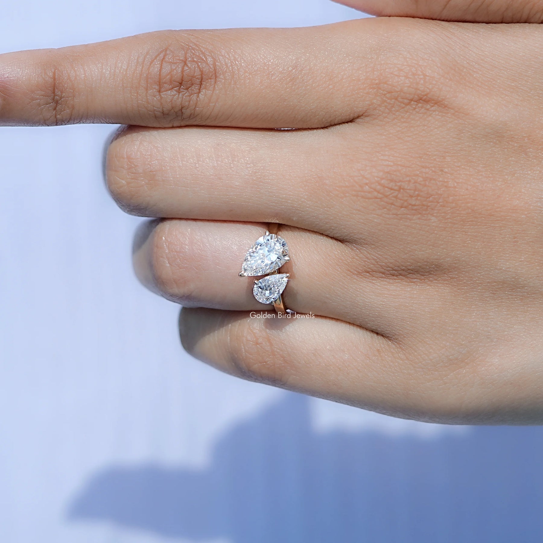 In finger front view of Pear Shaped Two Stone Ring in unique shape