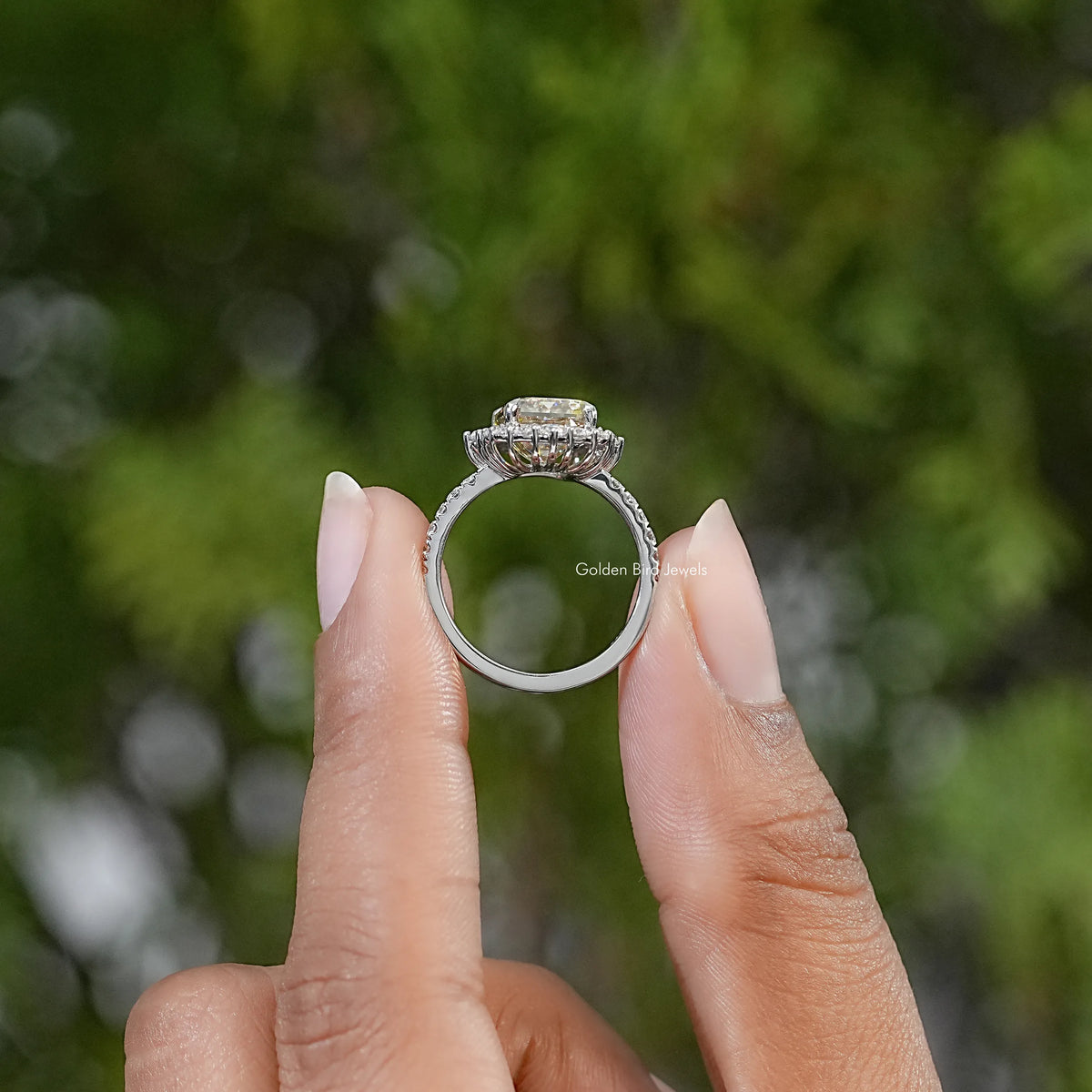 Sterling silver ring shown in profile, with raised emerald-cut center stone and halo
