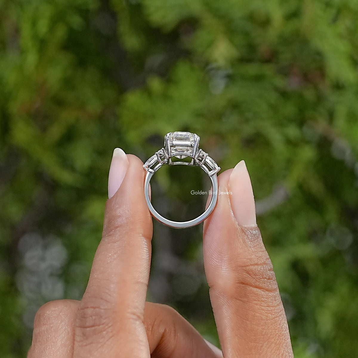 Side view of the silver ring showing the raised emerald-cut center stone and open setting.
