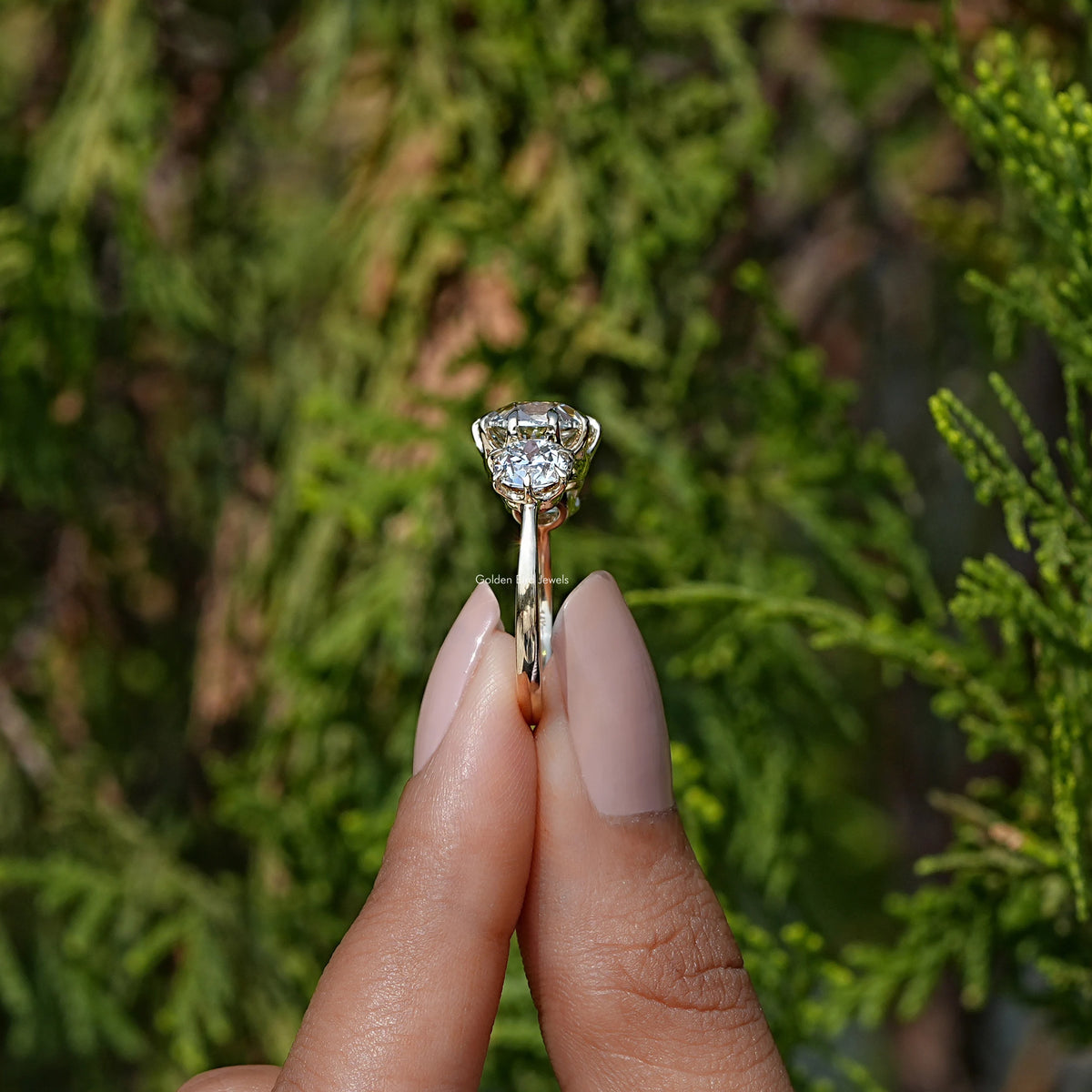 Side View of Cushion Cut Diamond Three Stone Engagement Ring In two fingers