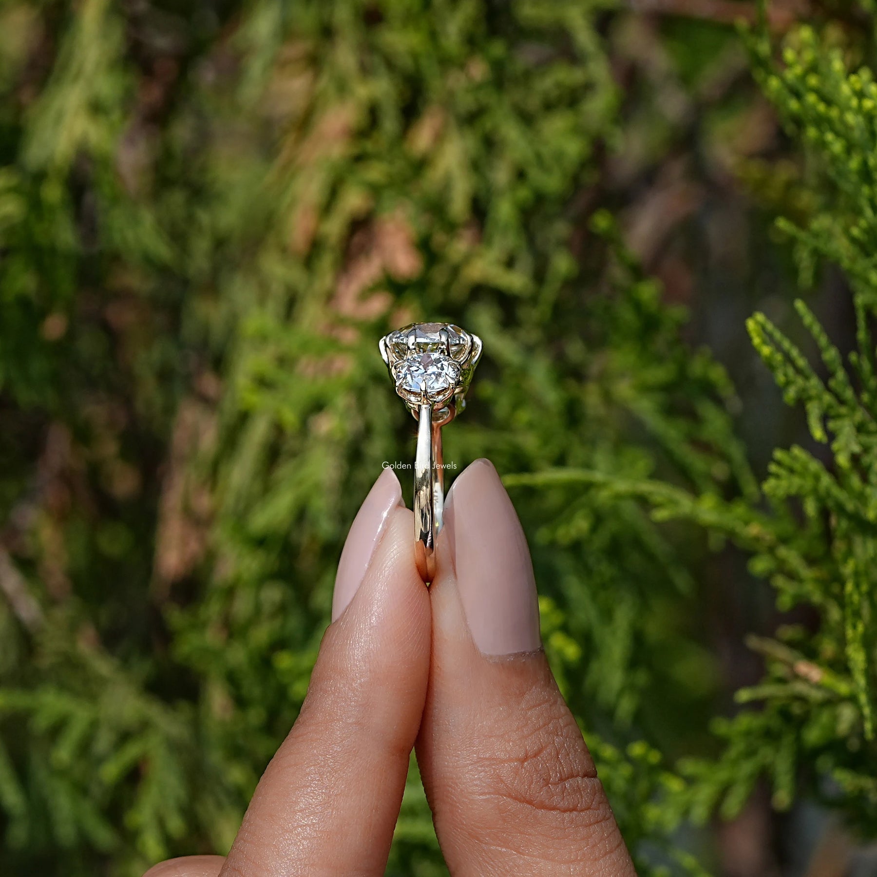 Side View of Cushion Cut Diamond Three Stone Engagement Ring In two fingers
