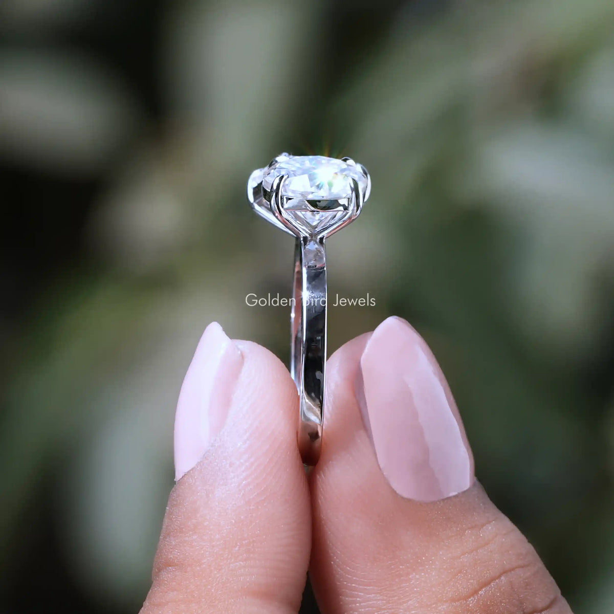 Side View of Emerald And Round Cut Moissanite Ring In two fingers