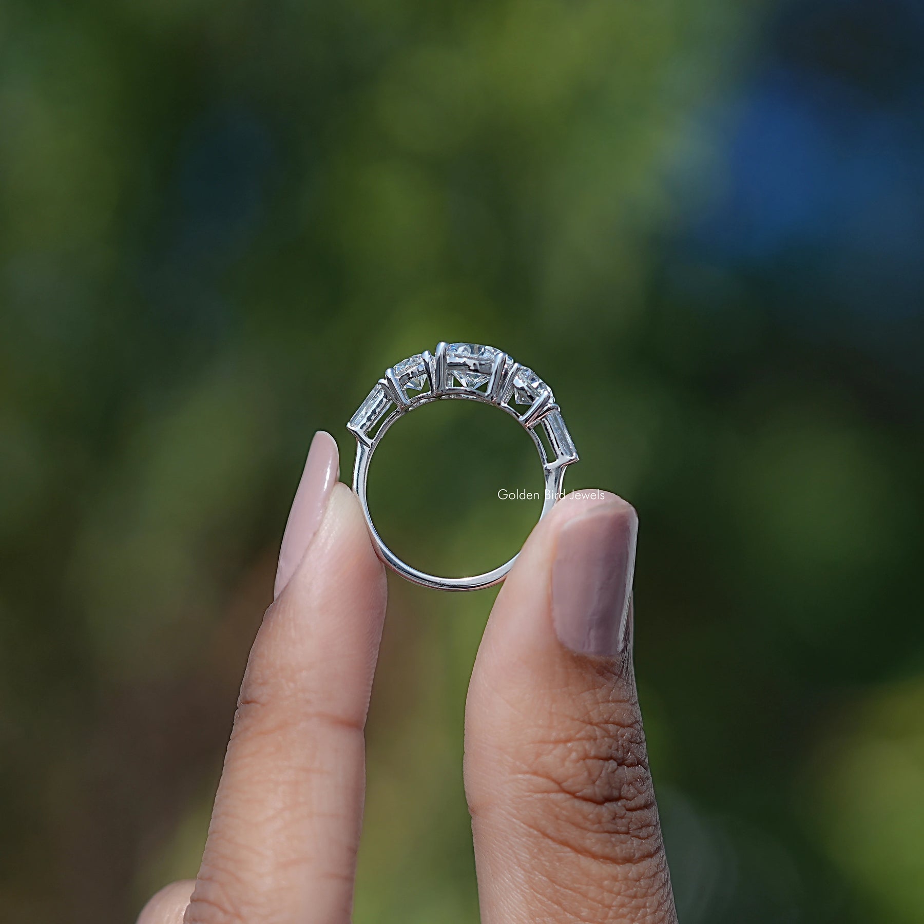 Back View of Round And Tapered Baguette Five Stone Ring In two fingers
