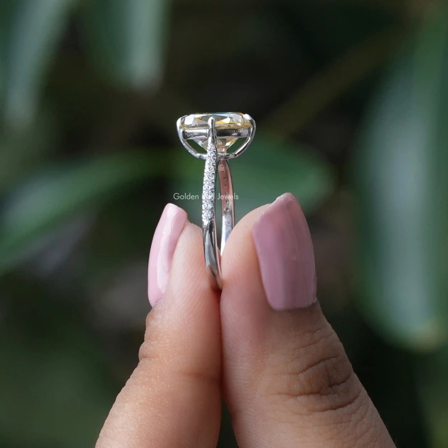 Side View of Cushion Cut Engagement Ring In two fingers