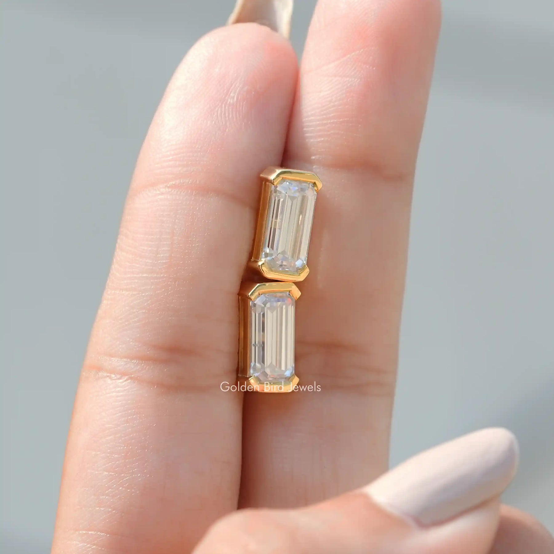 Emerald cut studs in half bezel setting in a secure setting