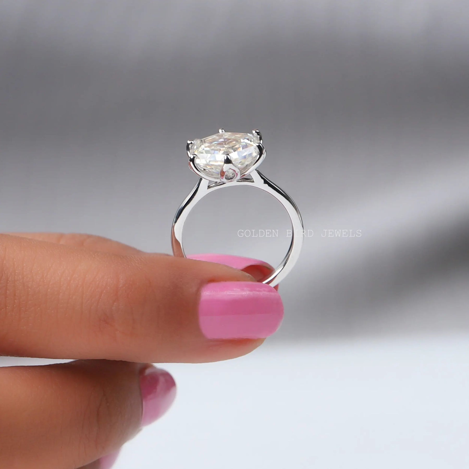 Back View of Moissanite Hexagon Cut Solitaire Engagement Ring In two fingers