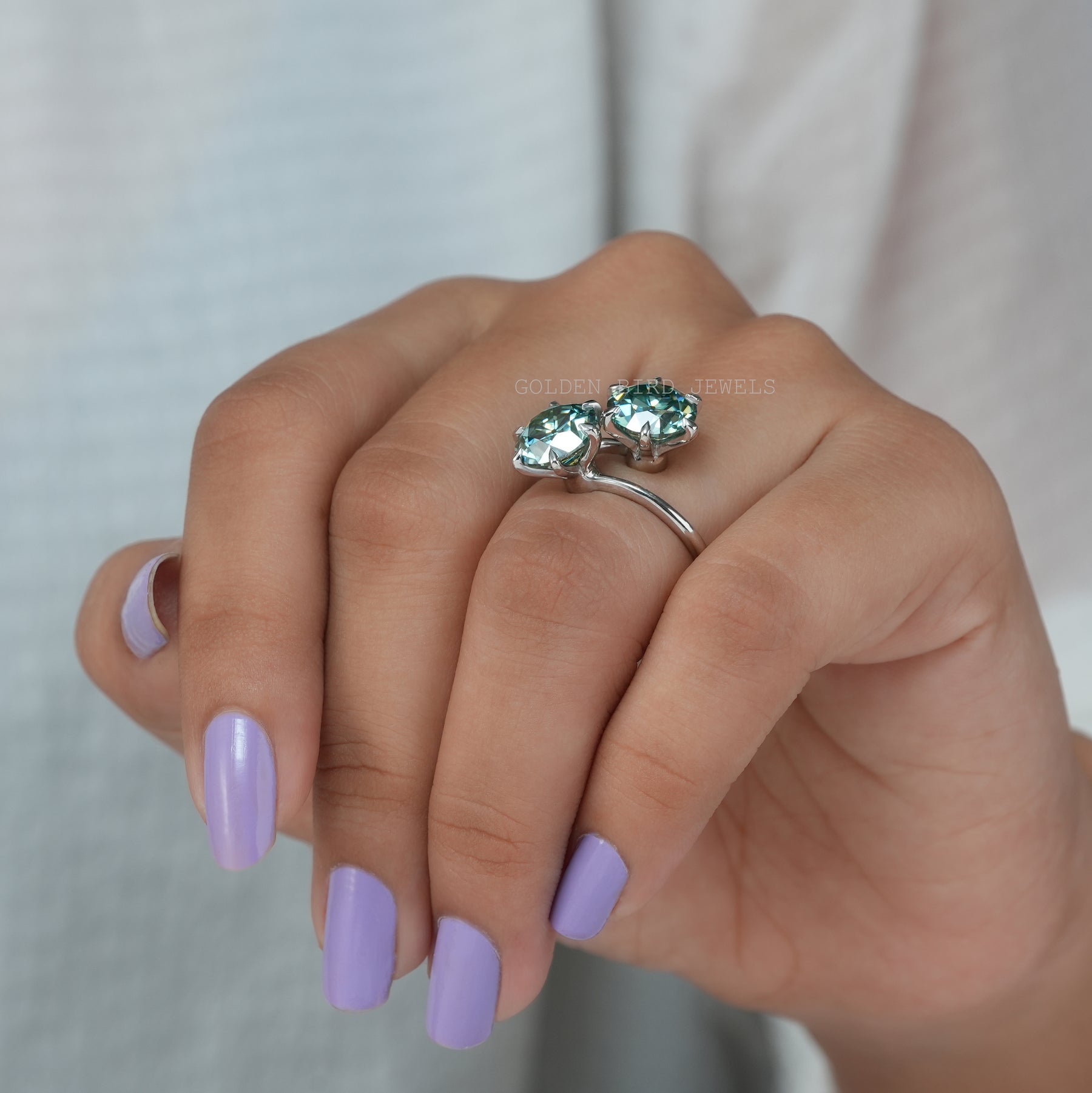 In finger front view of blue moissanite engagement ring