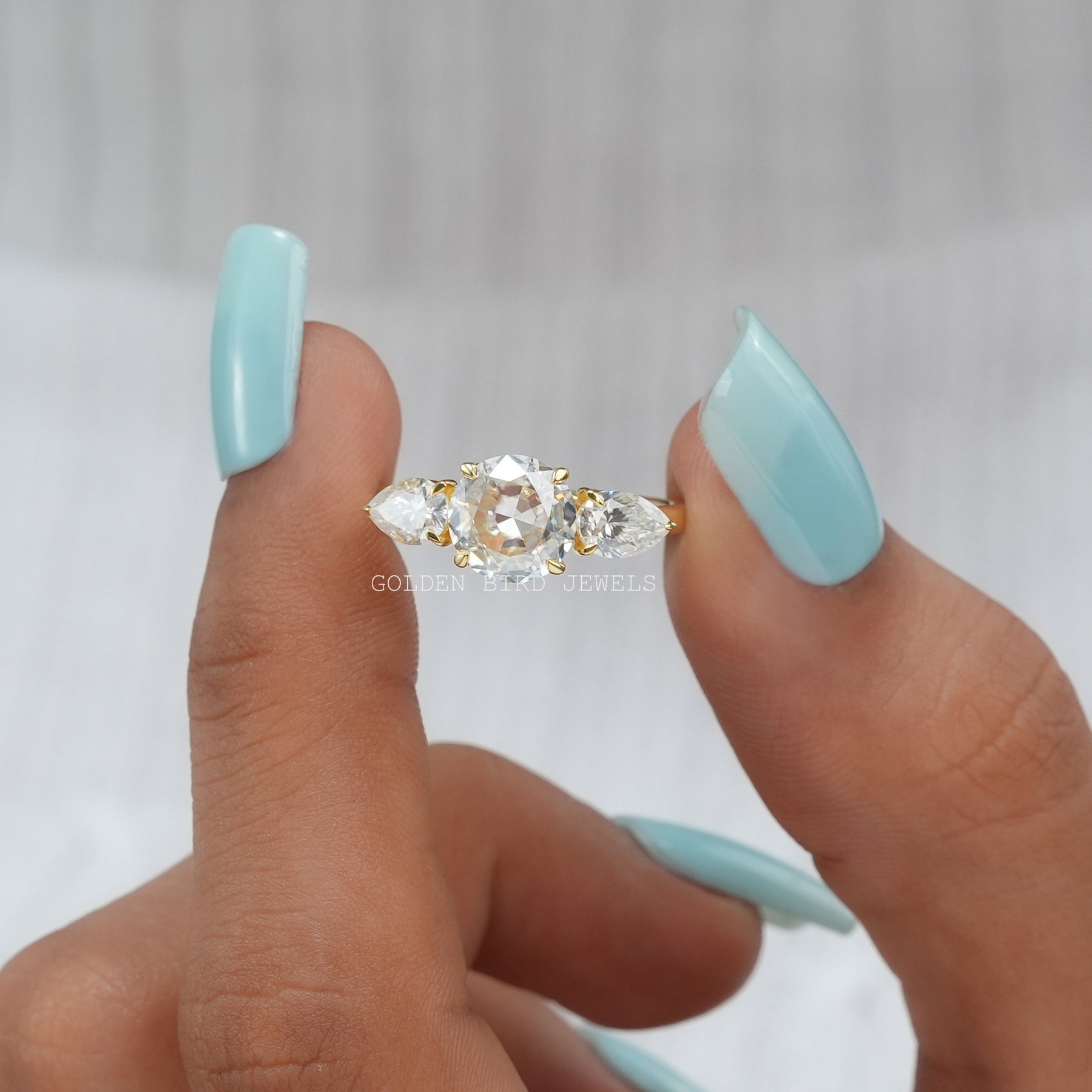 Front View of Round Cut Moissanite Three Stone Ring In two Fingers