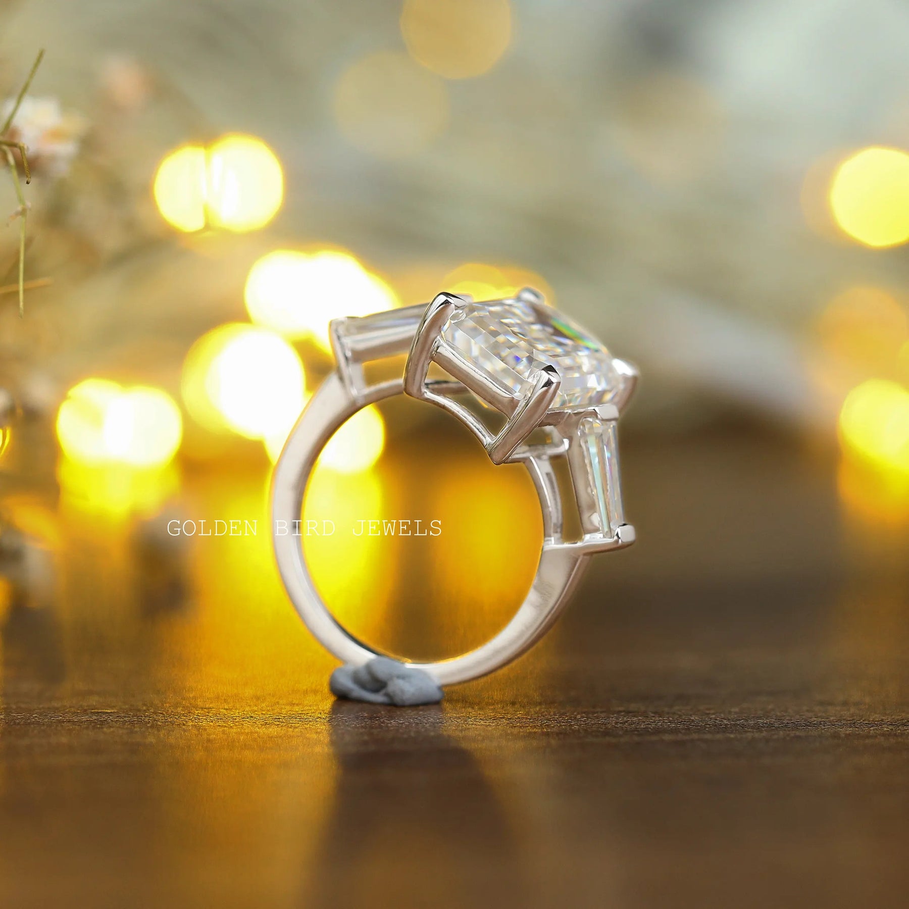 View of Three Stone Emerald Cut Moissanite Ring In Yellow Gold
