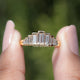Gold ring with emerald-cut diamonds on a blurred green background