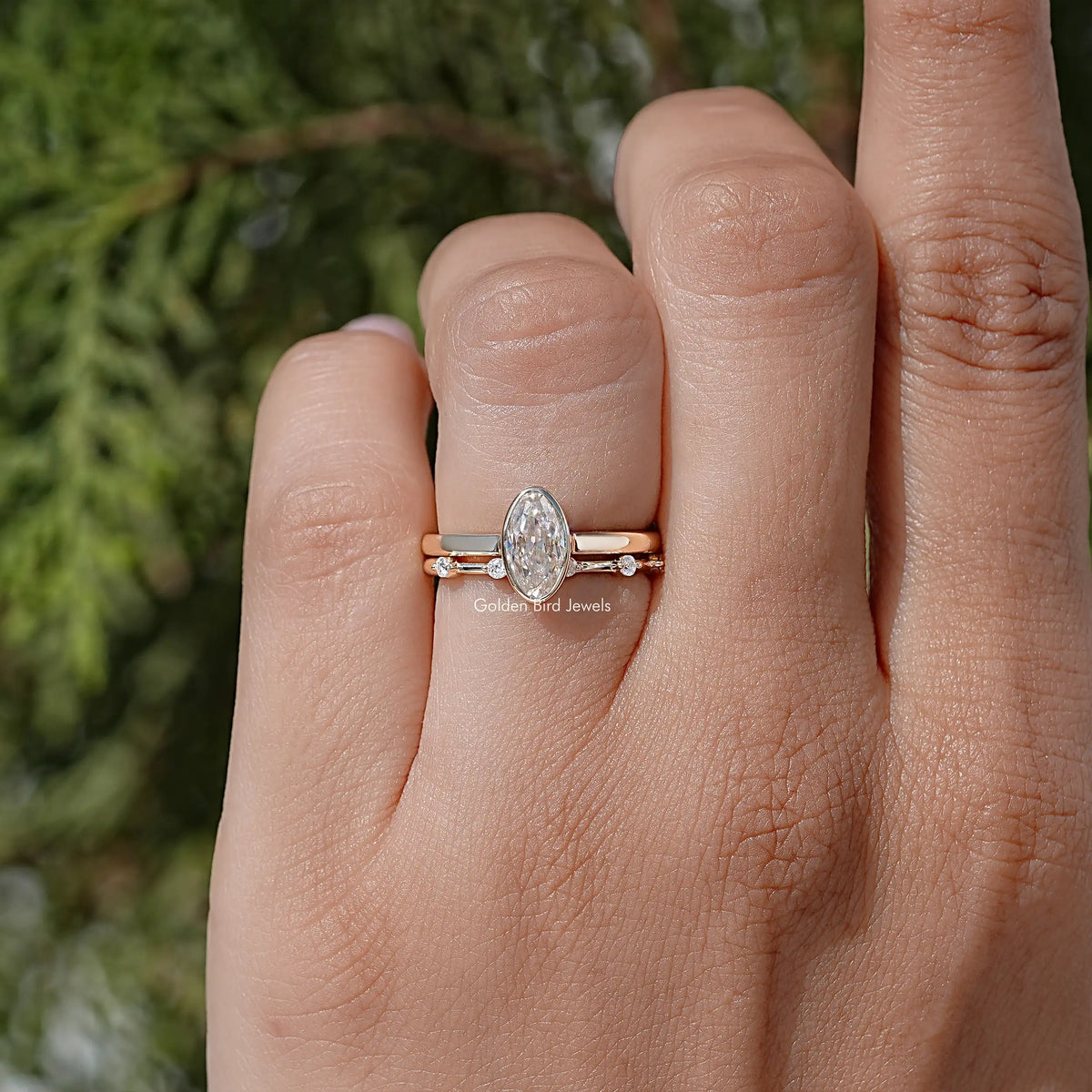 Oval solitaire bridal ring set stacked on a hand with thin accent bands