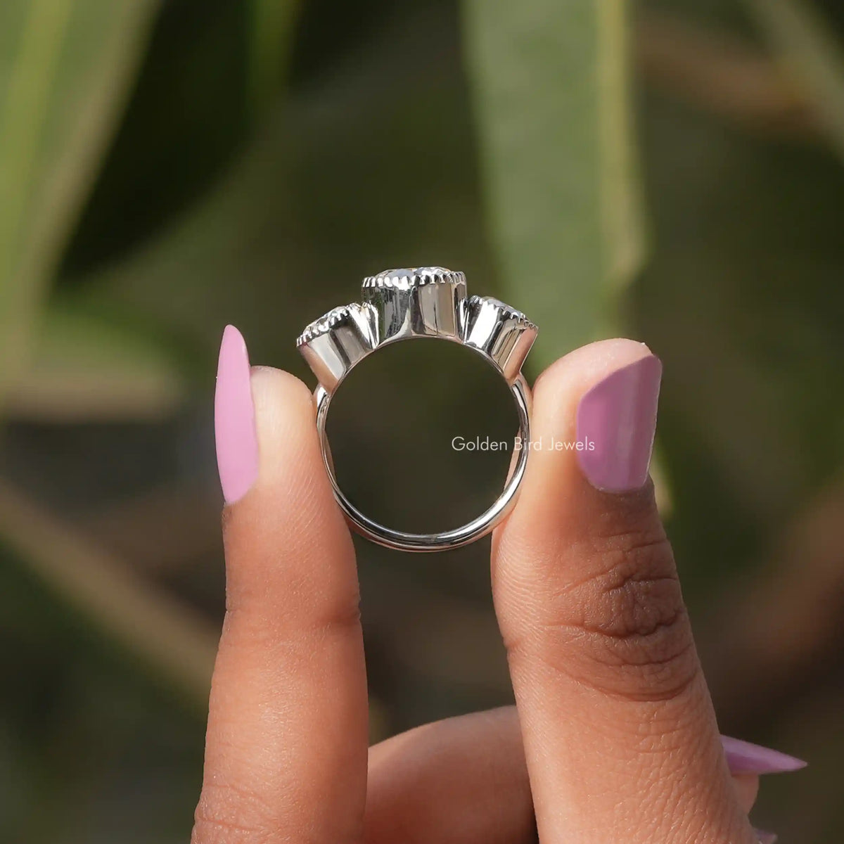 Back View of Three Stone Round Cut Moissanite Ring In two fingers