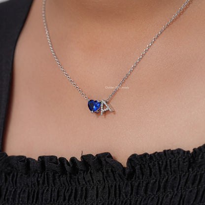 Silver chain necklace with blue heart gemstone pendant and A letter charm, close-up