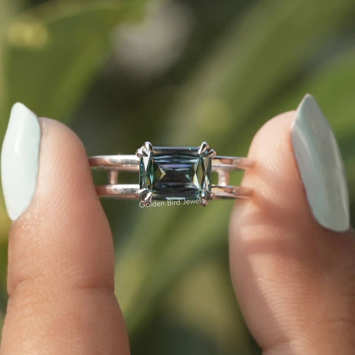 Two fingers holding the Double Set Blue Criss Cut Moissanite Solitaire Ring