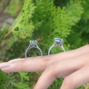 Back View of Blue Green Oval Cut Moissanite Solitaire Ring in two fingers