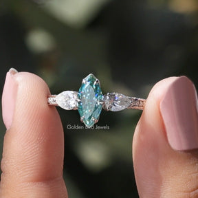 Two fingers holding the Blue Marquise Cut Moissanite Three Stone Ring