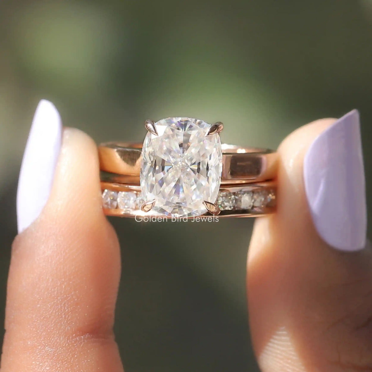 Two fingers holding the Colorless Cushion Cut Moissanite Bridal Ring Set