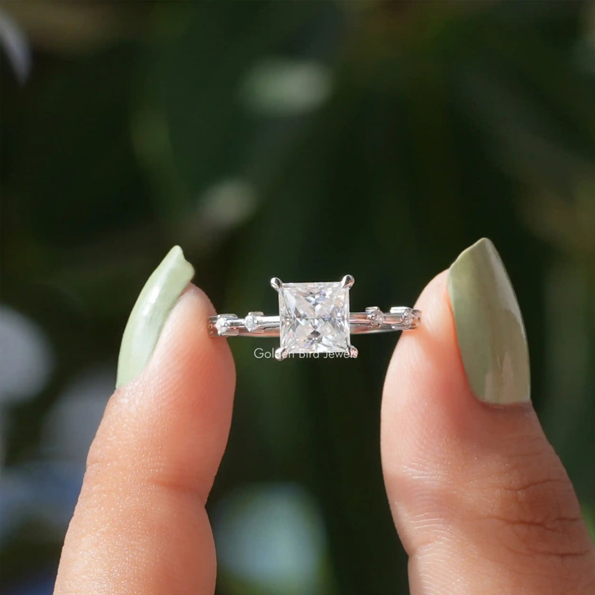 Two fingers holding the Princess Cut Moissanite Solitaire Ring