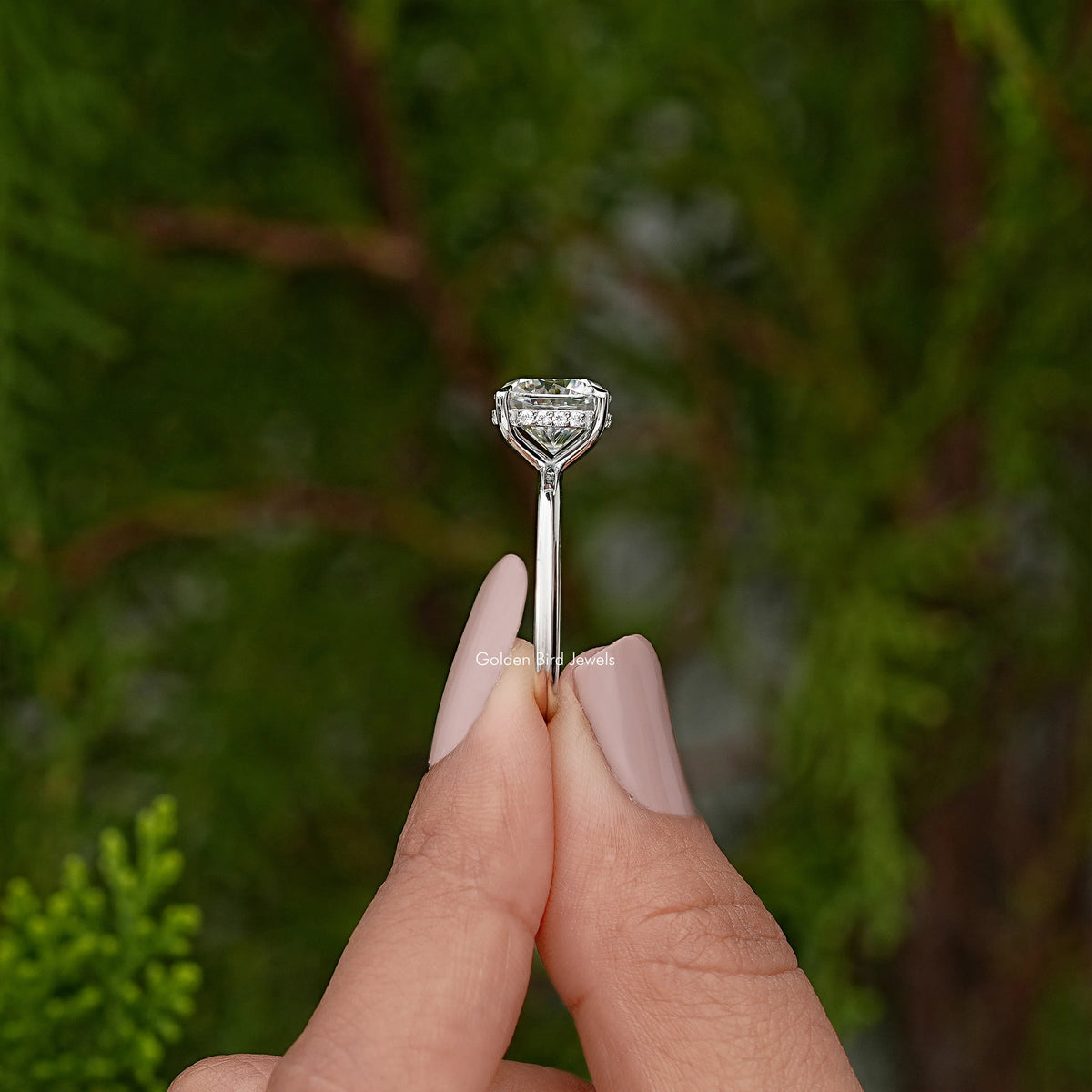 Solitaire ring held upright showing cushion-cut stone in prong setting on silver band