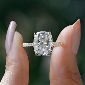 Front view of cushion cut moissanite engagement ring holding in two fingers 