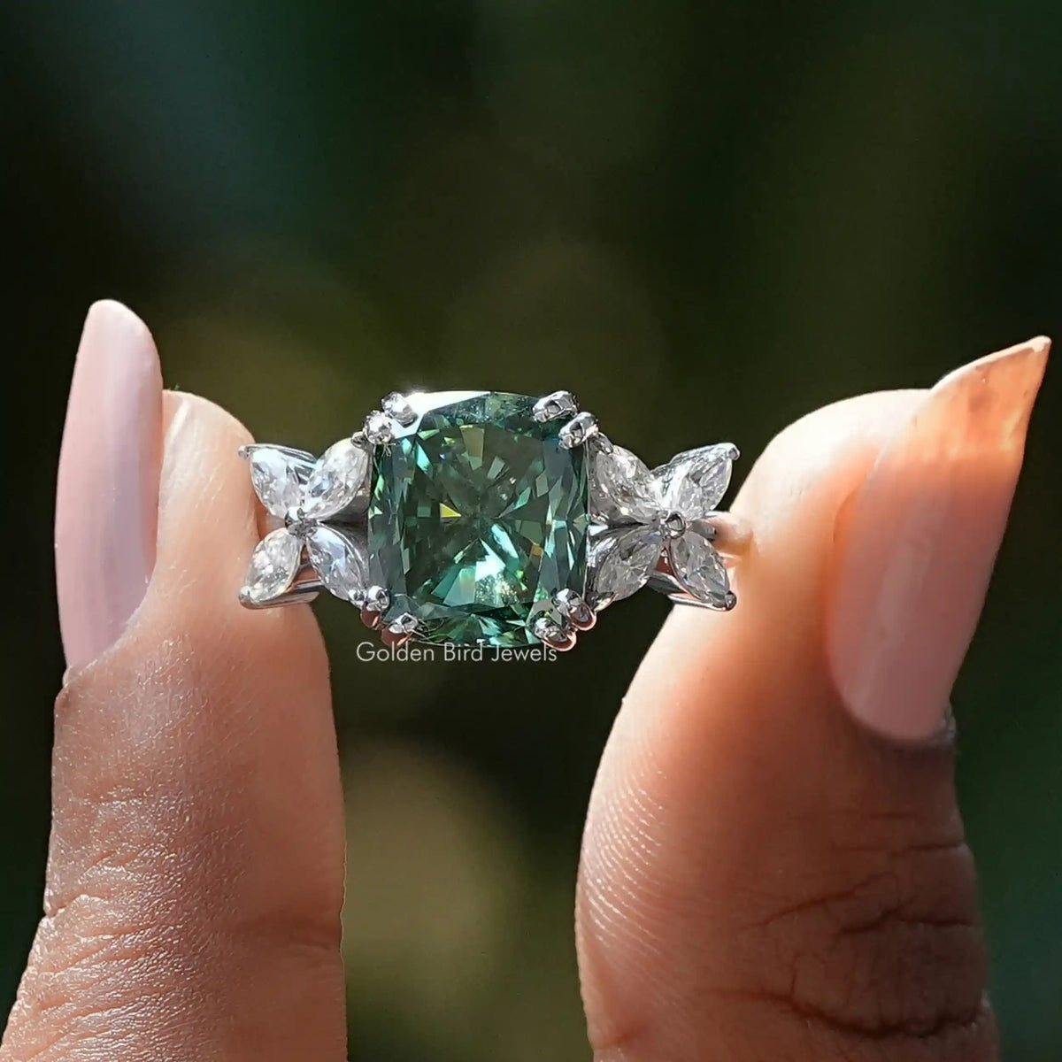 Two fingers holding the Dark Green Cushion Cut Moissanite Ring