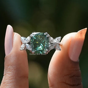 Two fingers holding the Dark Green Cushion Cut Moissanite Ring