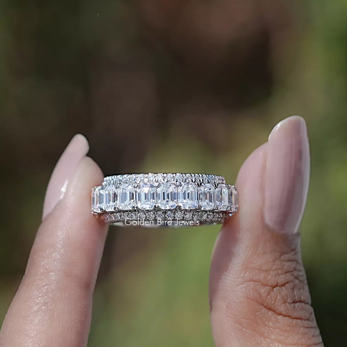 Front view of Emerald and Round Cut moissanite three row band in two fingers 
