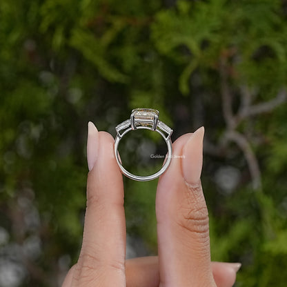 Sterling silver three-stone engagement ring shown from the side, with an emerald-cut center stone and open band